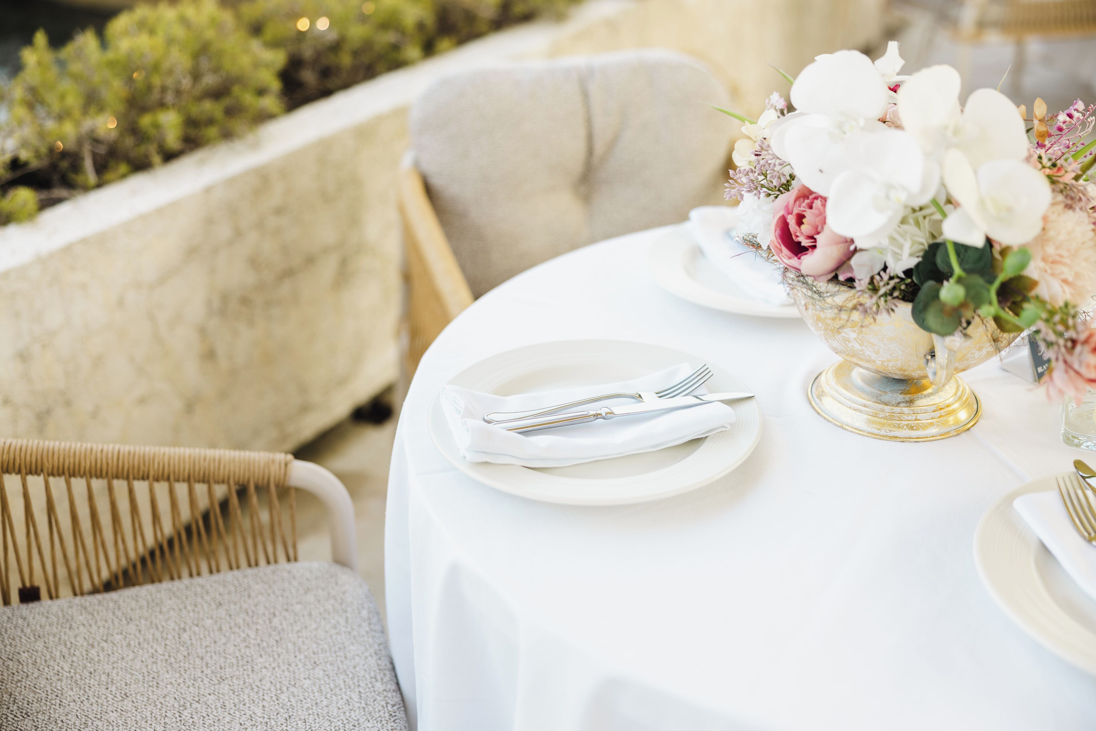 A table set for dining with white plates, silverware, and a floral centerpiece.