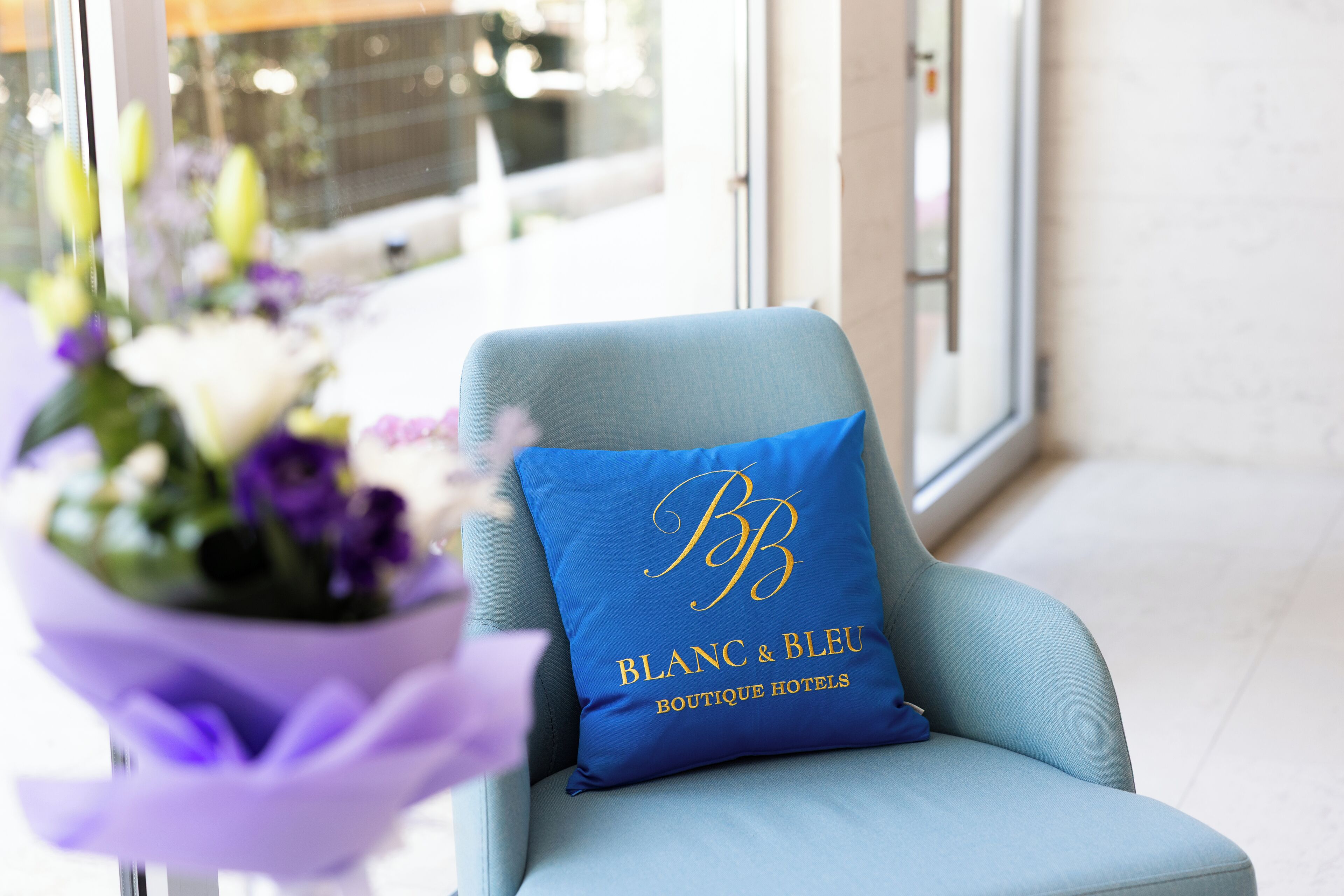 A chair with a pillow displaying 'Blanc & Bleu Boutique Hotels' logo.