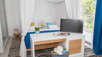 Un dormitori amb llit, televisió, escriptori i finestra amb cortines.