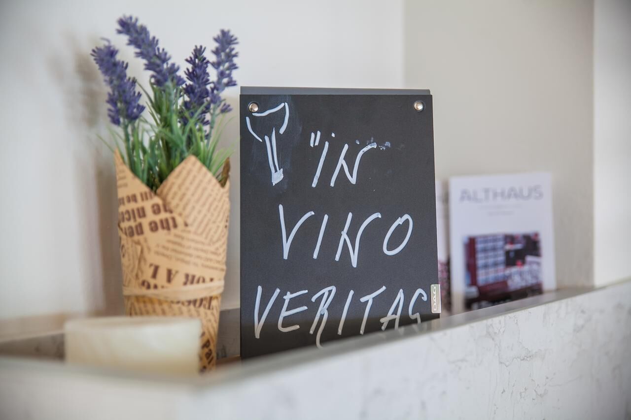 Una pissarra amb el text “IN VINO VERITAS” i una petita planta de lavanda.