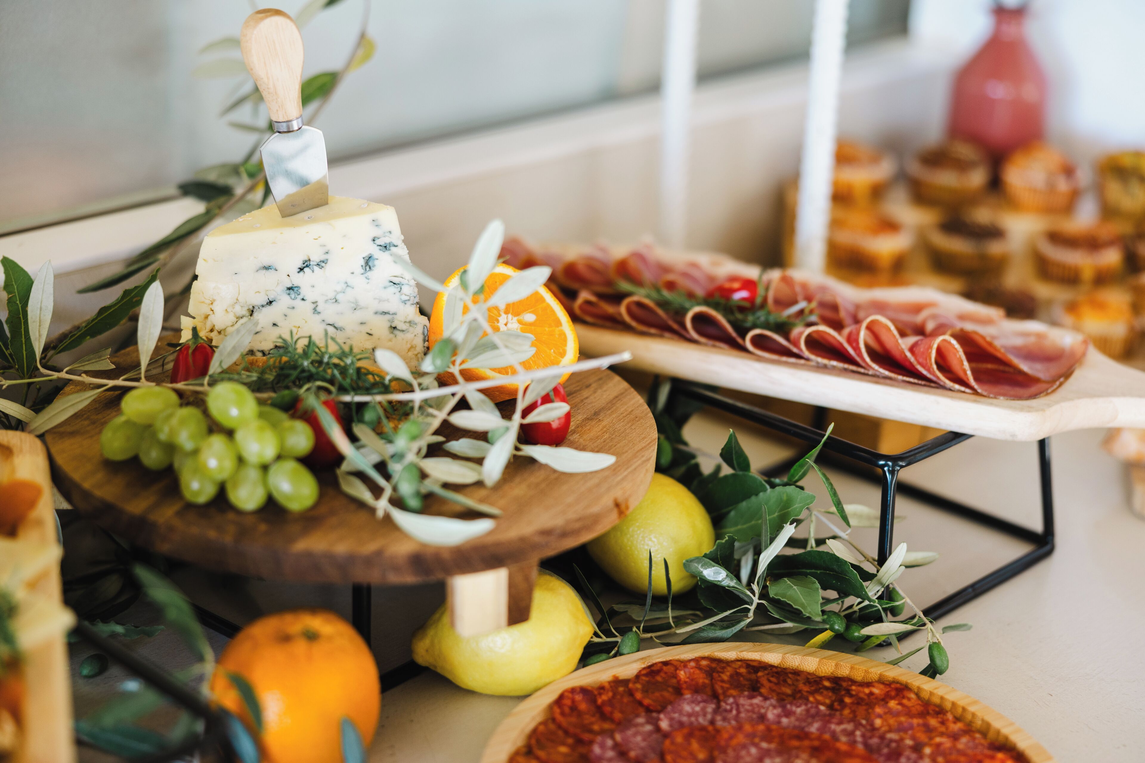 Una tabla de quesos con uvas, un limón y una pizza.