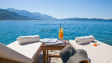 Een privéstrand, ligstoelen aan het strand, parasols, strandlakens