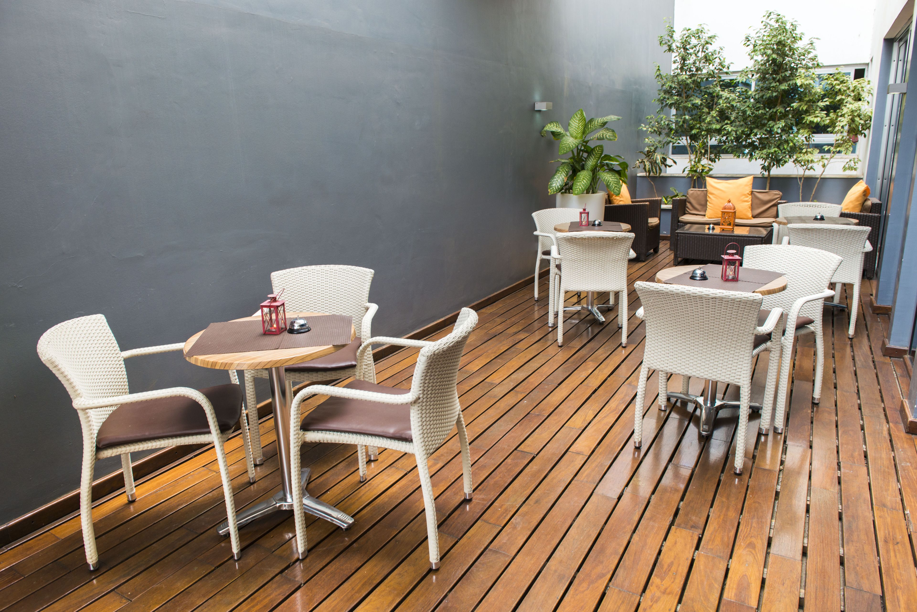 Un patio con mobiliario de mimbre, una mesa redonda y una planta en maceta.