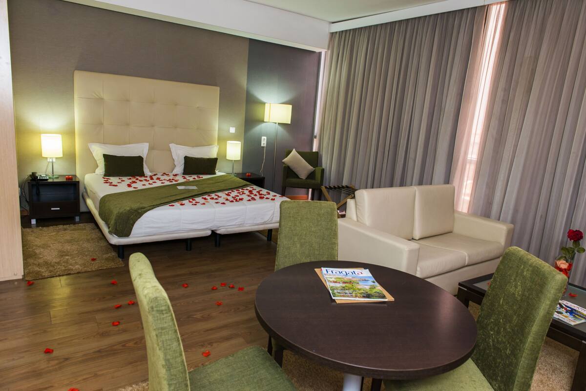Une chambre d’hôtel avec un grand lit, un canapé, une table ronde et une table de chevet avec une lampe.