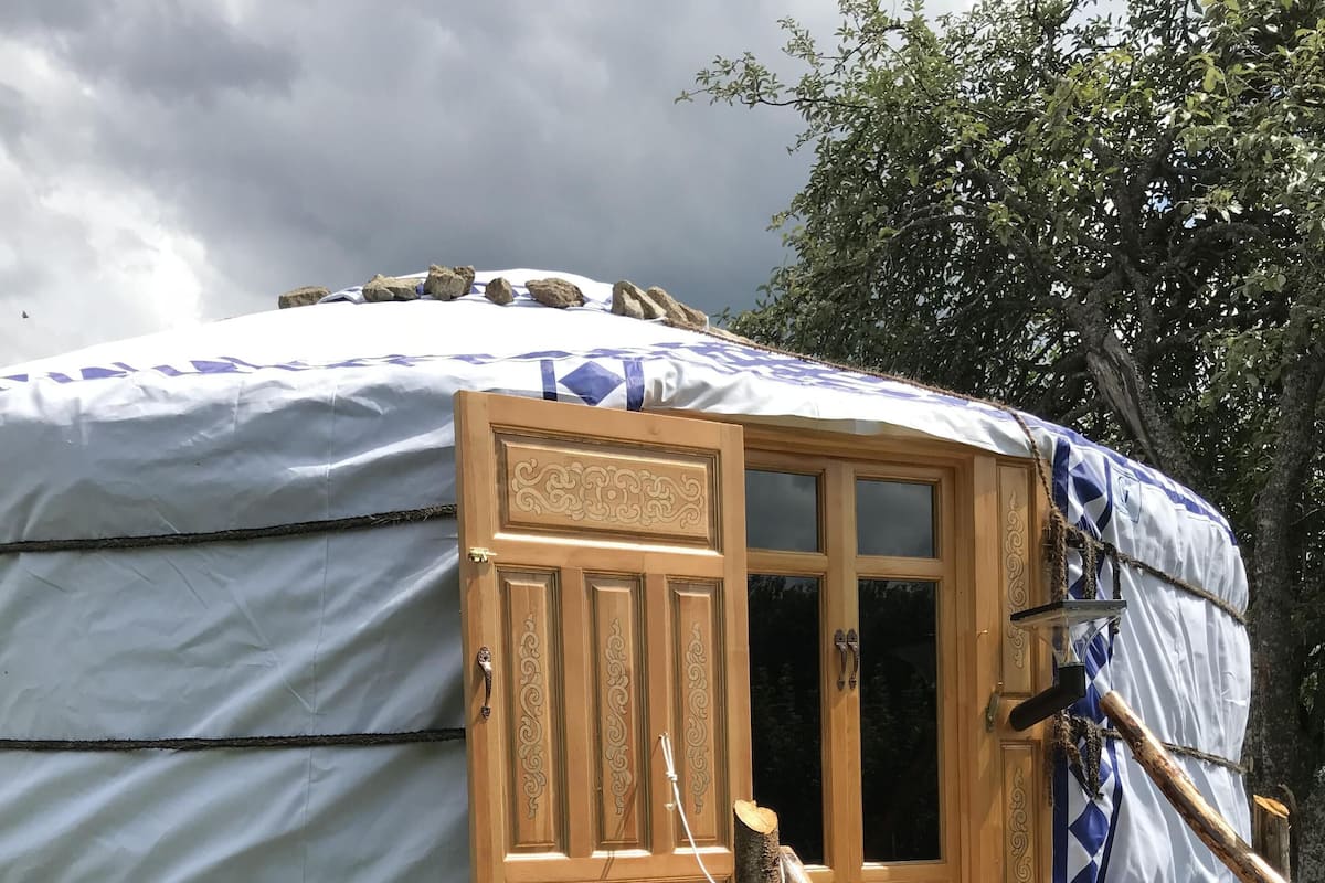 A yurt with a wooden door and a covered entrance.