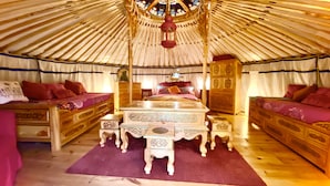 Ein traditionelles Jurten-Interieur mit einem zentralen Bett, zwei Betten an den Seiten und einer Zierkommode.