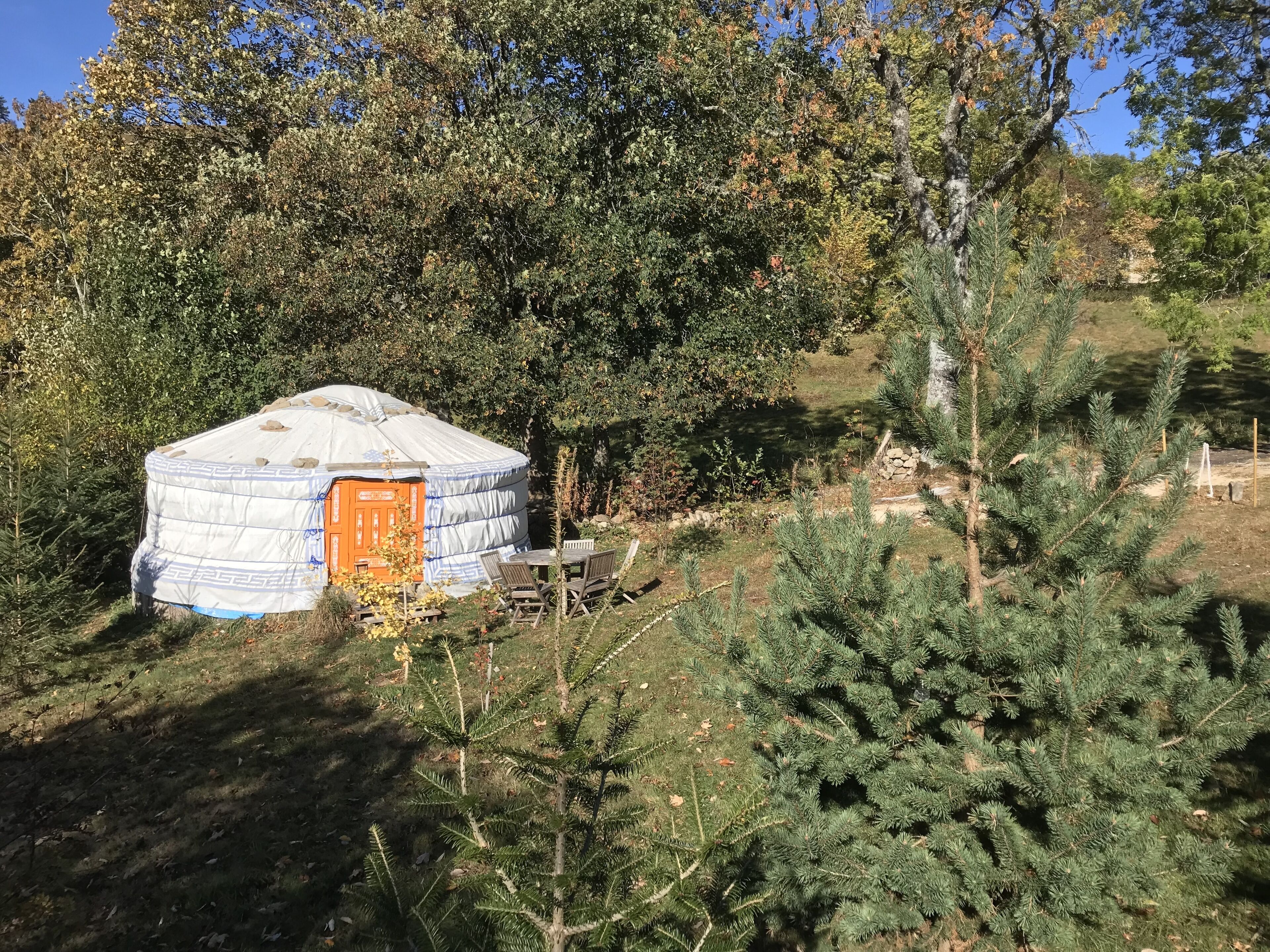 A yurt with a wooden door and a small table and chair set outside.