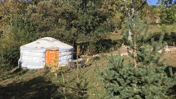 A yurt with a wooden door and a small table and chair set outside.