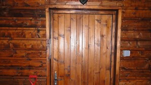 A wooden door with a metal handle, a red shovel, and a lantern above it. - Eco Yourte Les Airelles (Saint-Antheme)