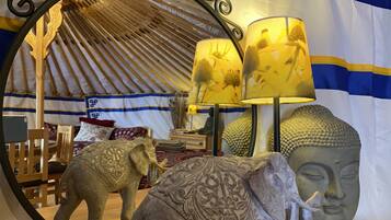 A room with a mirrored wall reflecting a yurt, a Buddha head sculpture, and an elephant statue.