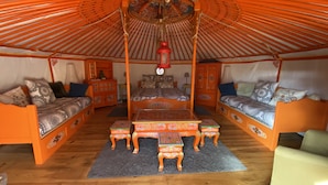 Ein traditionell eingerichteter Raum mit einem Himmelbett, zwei Sofas, einem Tisch und einer Hängelampe.