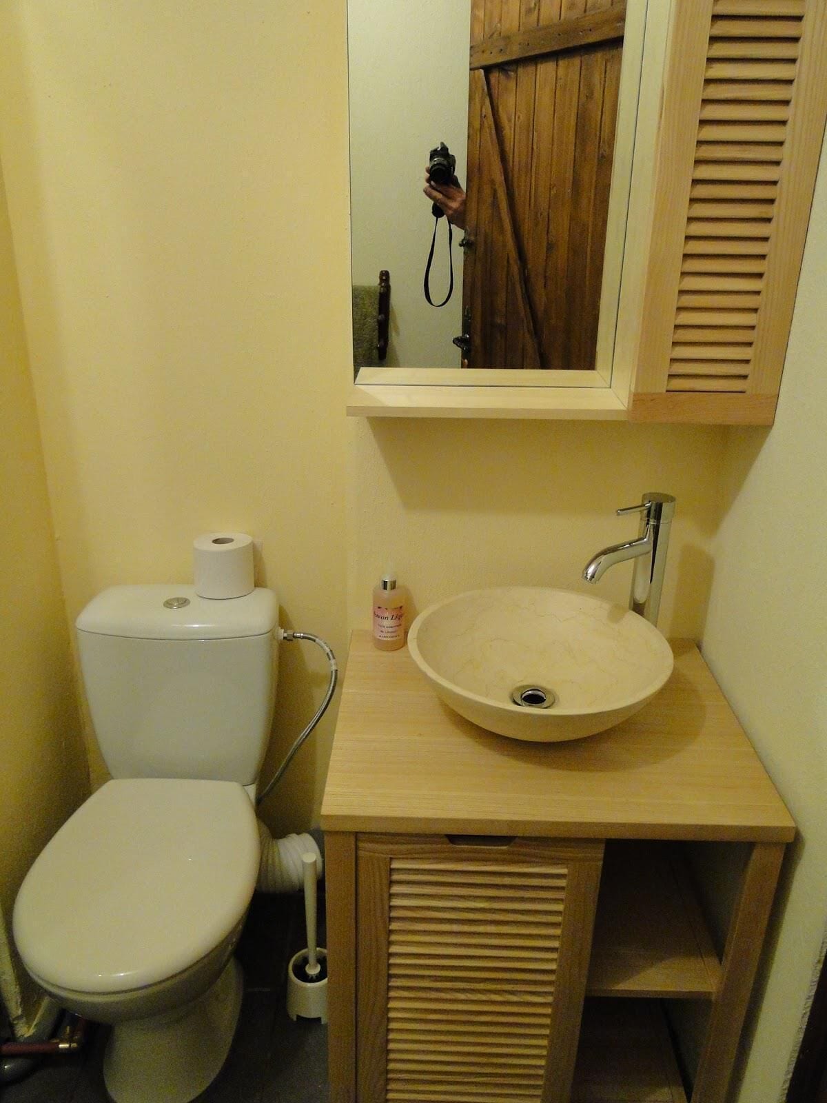 A small bathroom with a toilet, sink, and mirror.
