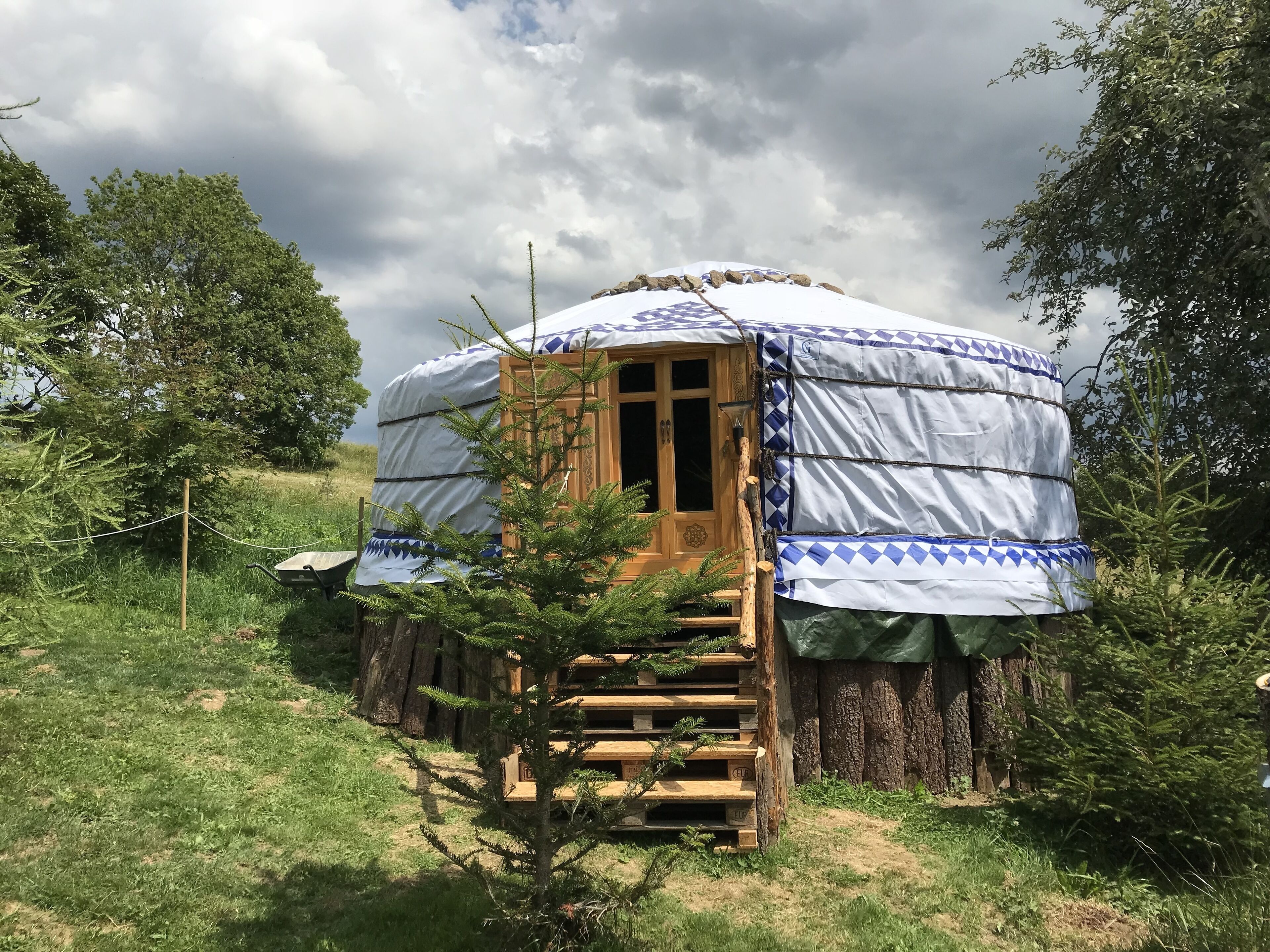 Una yurta con una porta di legno, circondata da alberi e erba.
