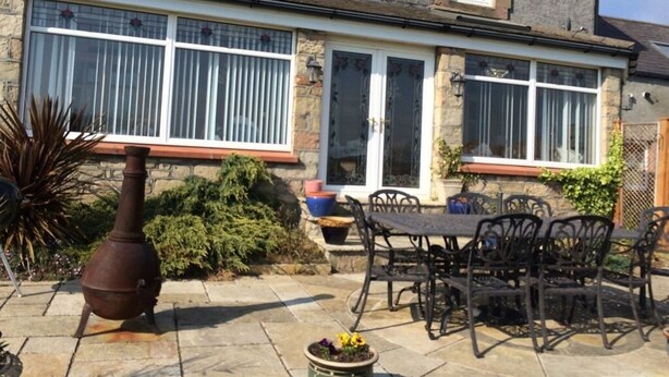 A stone house with a patio, a large metal pot, and outdoor furniture. - The old Farm House (Berwick-upon-Tweed)