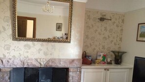 A living room with a fireplace, a television, and a cabinet with items on top. - The old Farm House (Berwick-upon-Tweed)