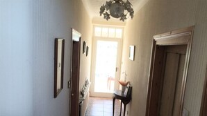 A hallway with a tiled floor, a door on the right, and a small table with a lamp in the center. - The old Farm House (Berwick-upon-Tweed)