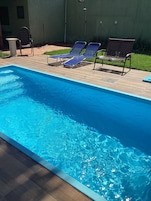 Una piscina al aire libre, sillones reclinables de piscina
