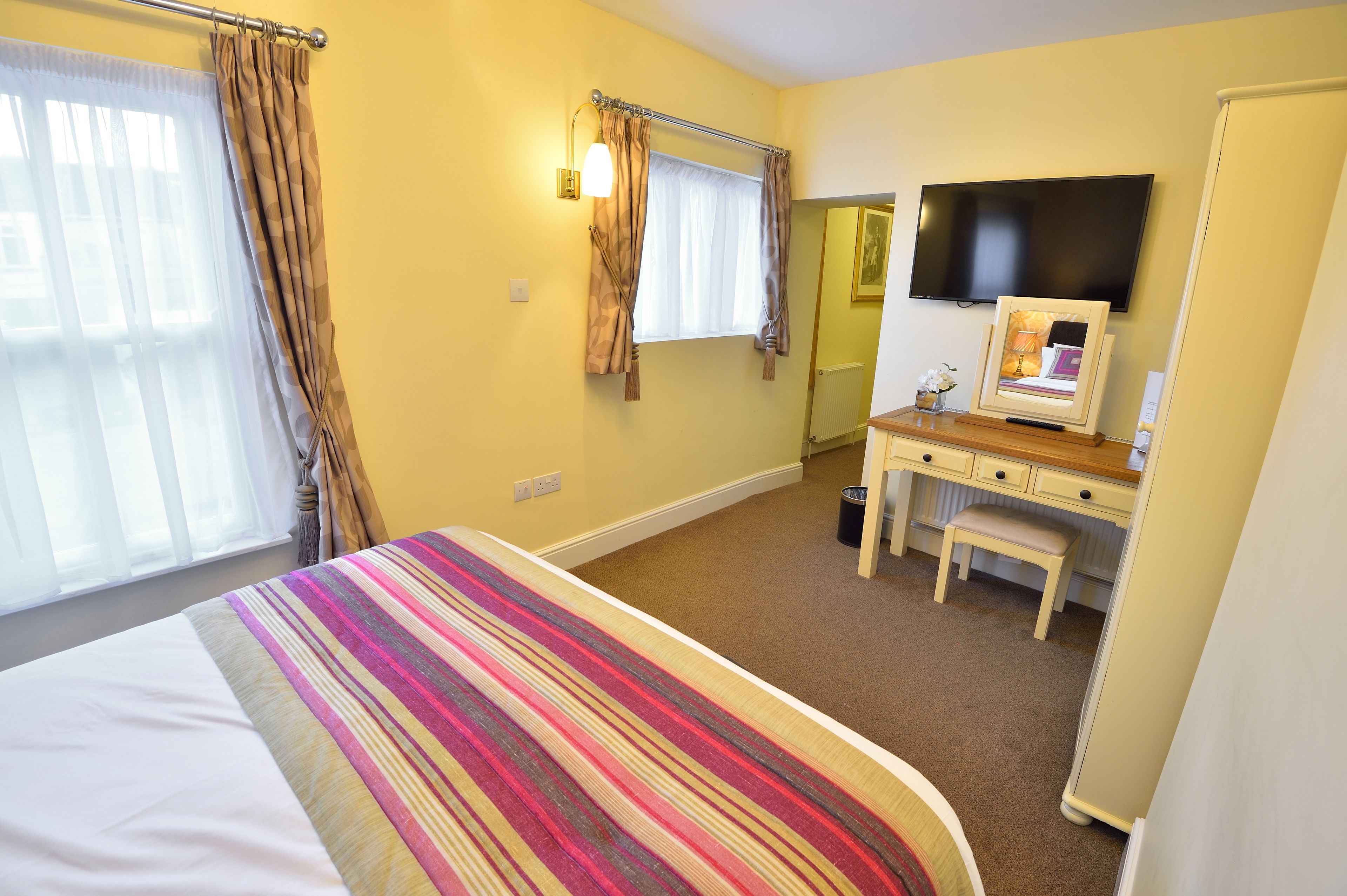 A hotel room with a bed, a desk, a chair, a television, and a window with curtains.