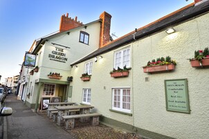 Un edificio con un letrero que dice "The Green Dragon Accommodation" y un cartel anunciando "Bar acogedor, cervezas artesanales, comida disponible, habitaciones con baño privado."