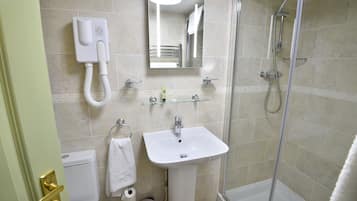Un baño con lavamanos blanco, espejo, cabezal de ducha de mano y retrete.