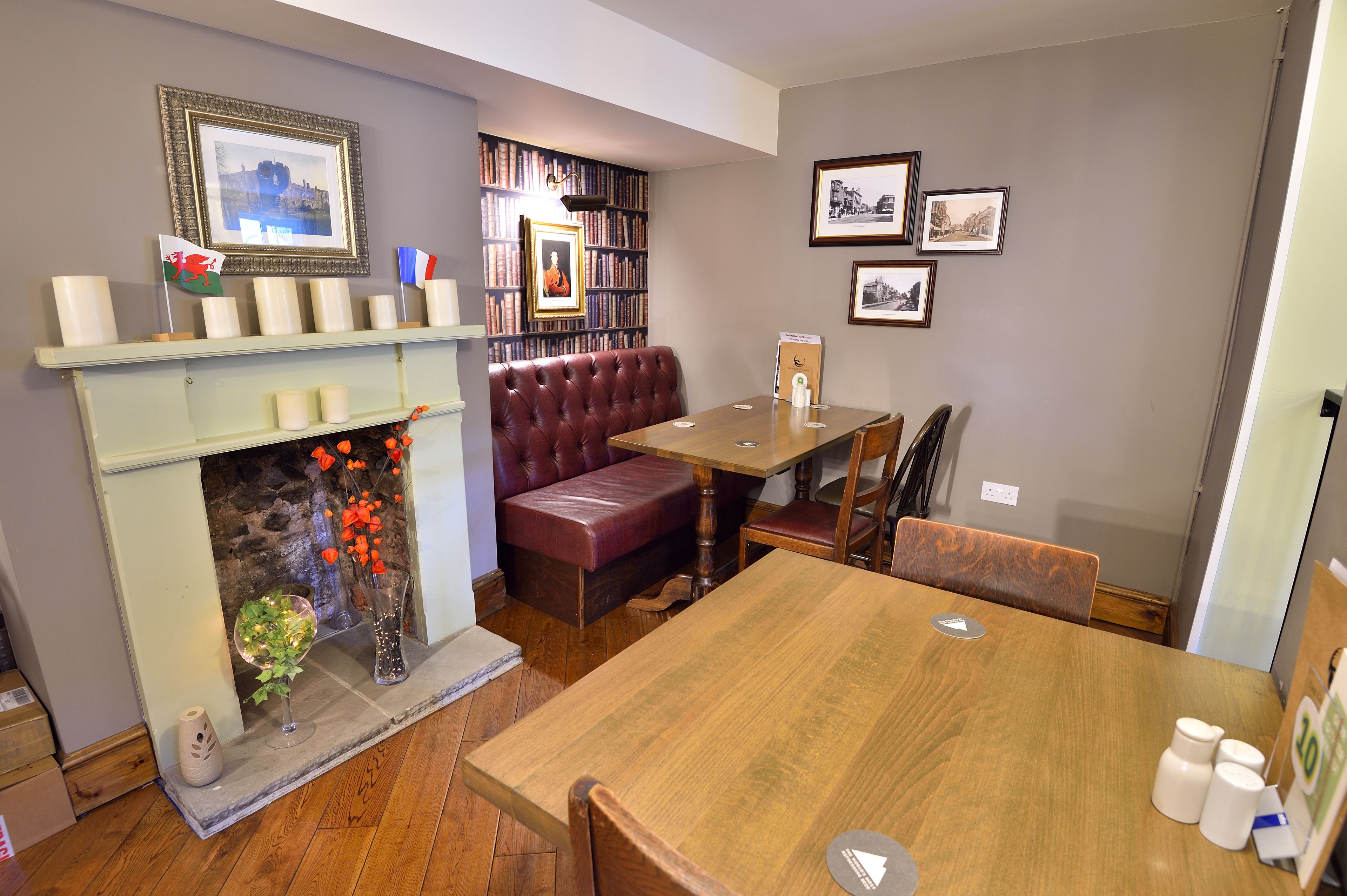 Una habitación acogedora con chimenea, estanterías, una mesa de comedor y un banco de cuero rojo.