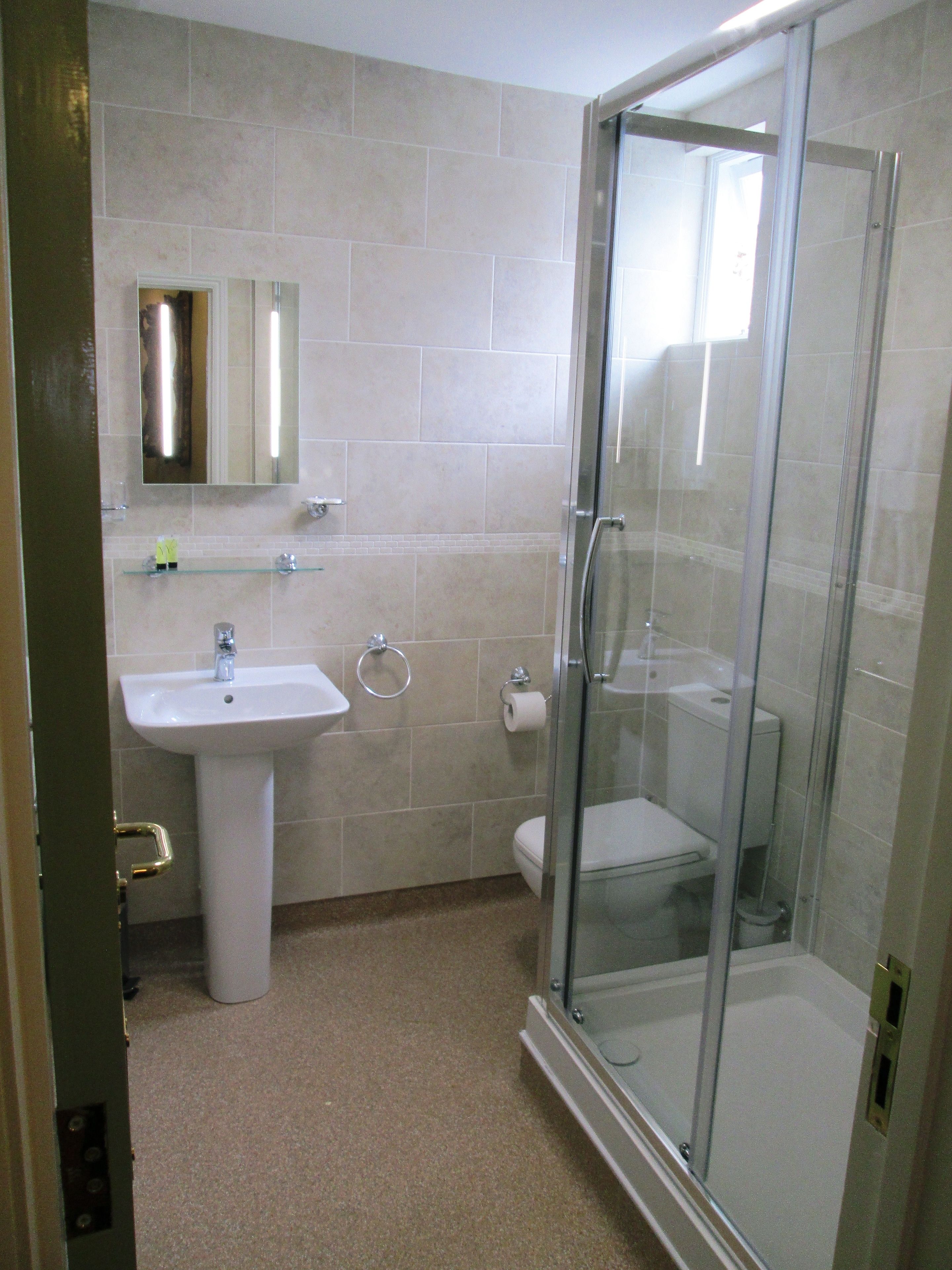Un baño con ducha acristalada, lavamanos e inodoro.