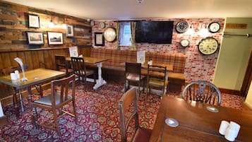 Un accogliente ristorante con pareti in legno, diverse pendole e un tappeto rosso con motivi.