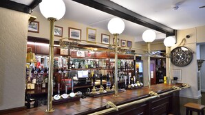 A bar area with a wooden counter, multiple beer taps, and a large clock on the wall. - The Green Dragon (Wellington)