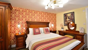 A neatly arranged bedroom with a wooden bed, two bedside tables with lamps, a mirror, and a framed picture on the wall. - The Green Dragon (Wellington)