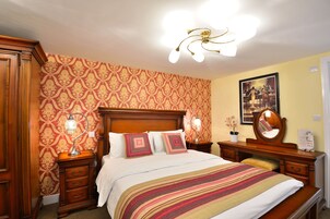 Un dormitorio ordenado con una cama de madera, dos mesitas de noche con lámparas, un espejo y un cuadro en la pared.