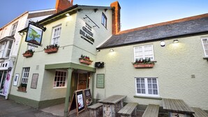 A traditional pub with a green exterior, wooden benches outside, and a sign advertising 'The Green Dragon Accommodation'. - The Green Dragon (Wellington)