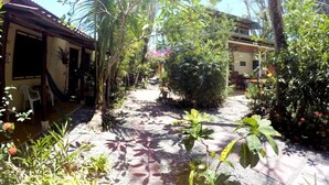 A courtyard with a hammock, potted plants, and a pathway. - Tropical Sands Dominical Eco Inn (Bahía Ballena)