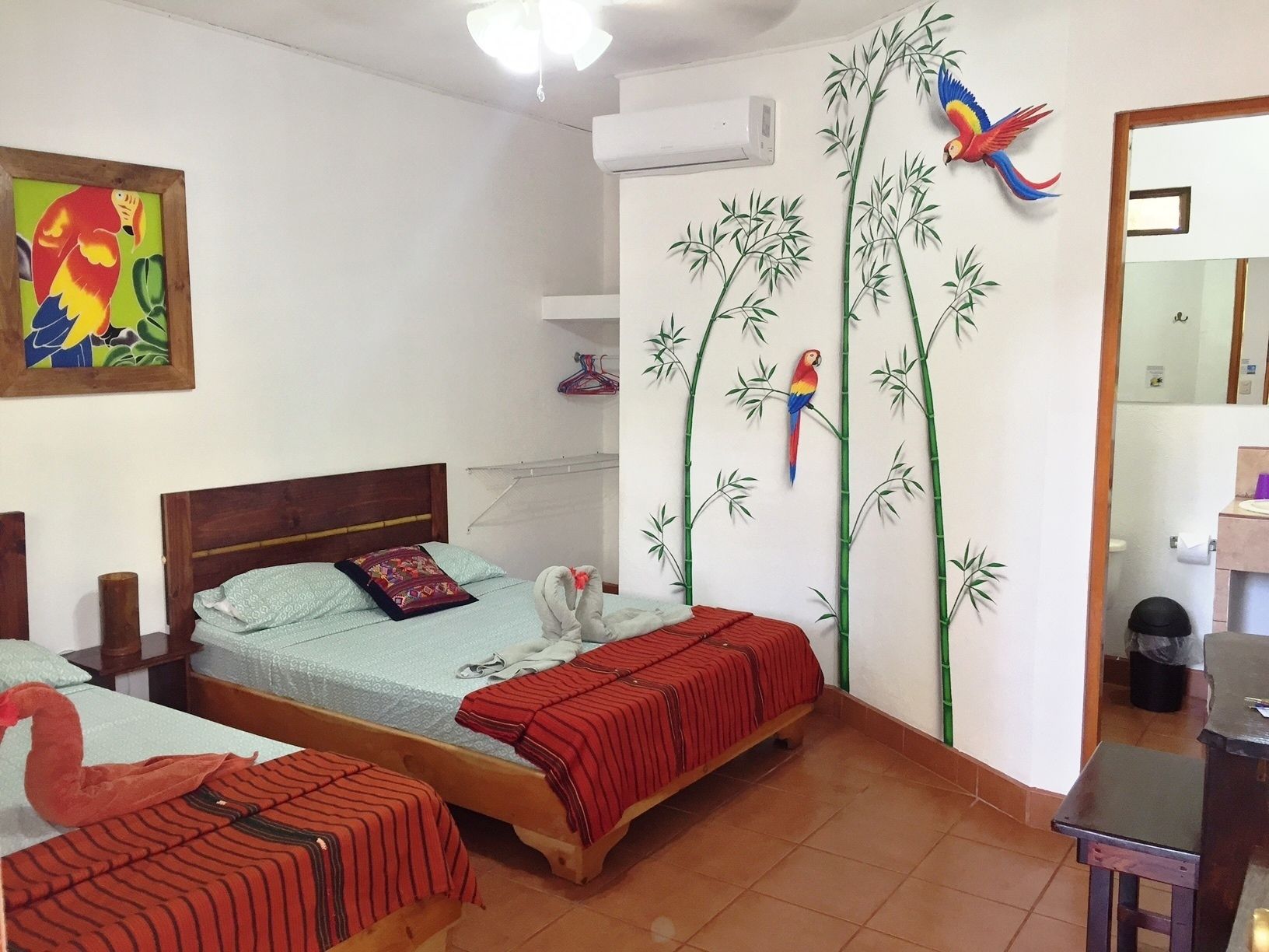 A bedroom with two beds, a wooden headboard, a wall-mounted air conditioner, and a mirror.