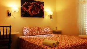 Une chambre d’hôtel avec un lit, une chaise, une table de chevet et un tableau accroché au mur.