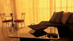 Un salon avec une table basse en verre, un canapé avec des coussins et deux fauteuils.