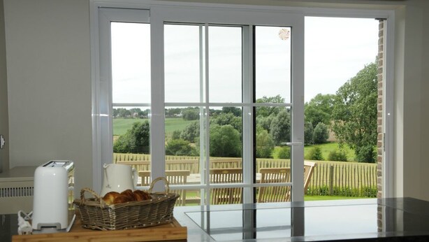 A kitchen with a large window, a toaster, a pitcher, and a basket of bread on the counter. - Guesthouse La Cereza (Brakel)