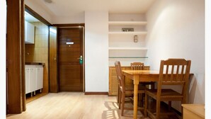 A room with a wooden dining table and chairs, a white cabinet, and a wooden door. - Apartamentos Goya 75 (Madrid)