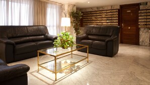 A living room with two leather sofas, a glass coffee table, a lamp, and a bookshelf. - Apartamentos Goya 75 (Madrid)