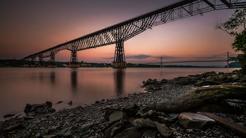 Uma ponte de aço sobre águas calmas ao entardecer.