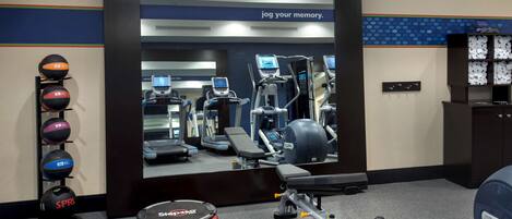 A gym area with treadmills, a step platform, dumbbells, and a variety of exercise balls.