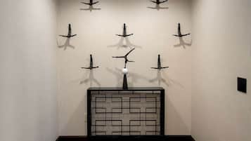A hallway with a black metal bench and a wall-mounted sculpture.