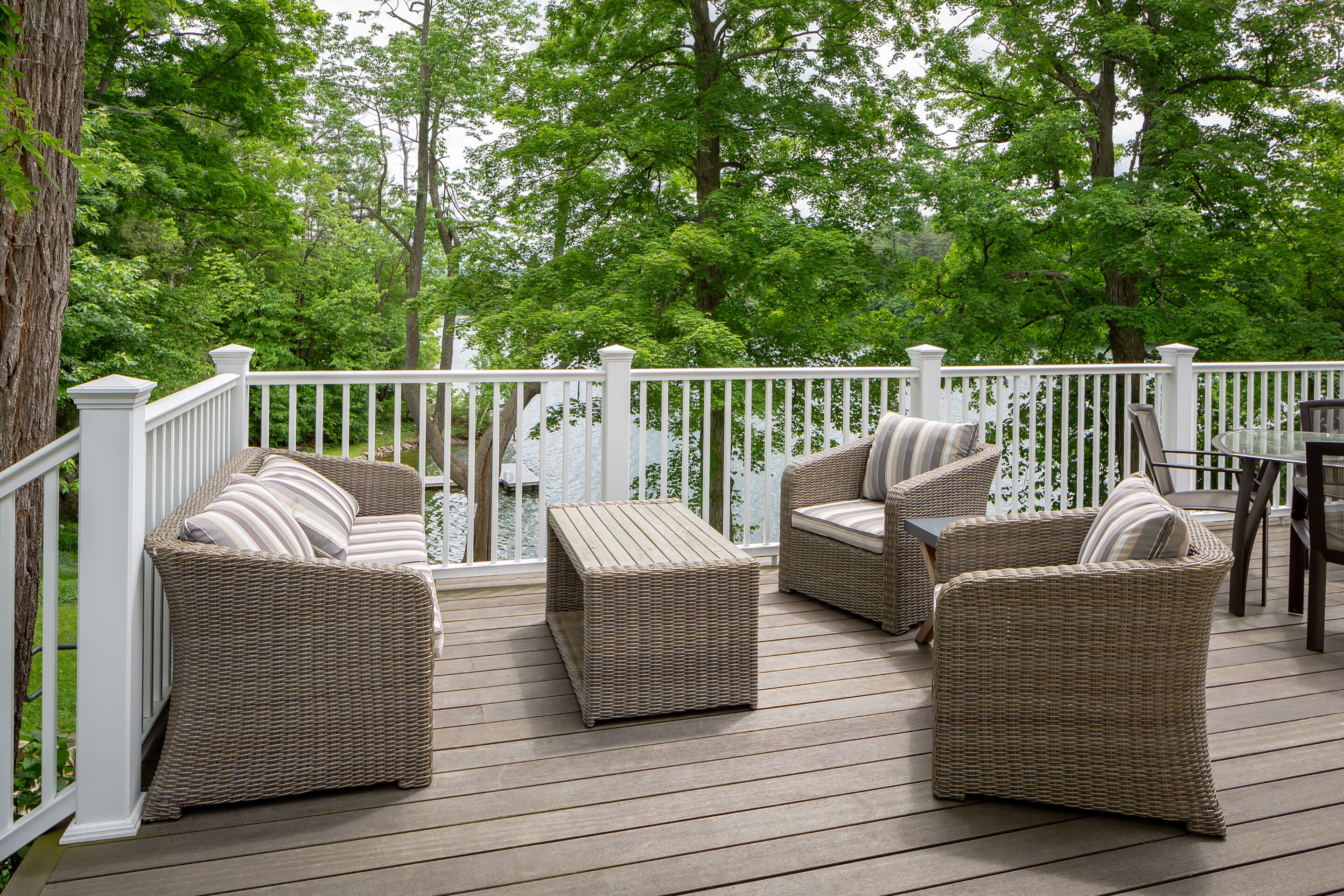 A deck with wicker furniture and a white railing.