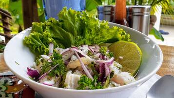 Un tazón de ensalada de mariscos con lechuga, cebollas rojas y lima sobre una mesa de madera.