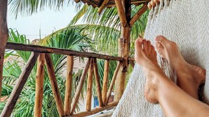 A hammock under a wooden structure with a view of palm trees. - Nayal Lodge (León)