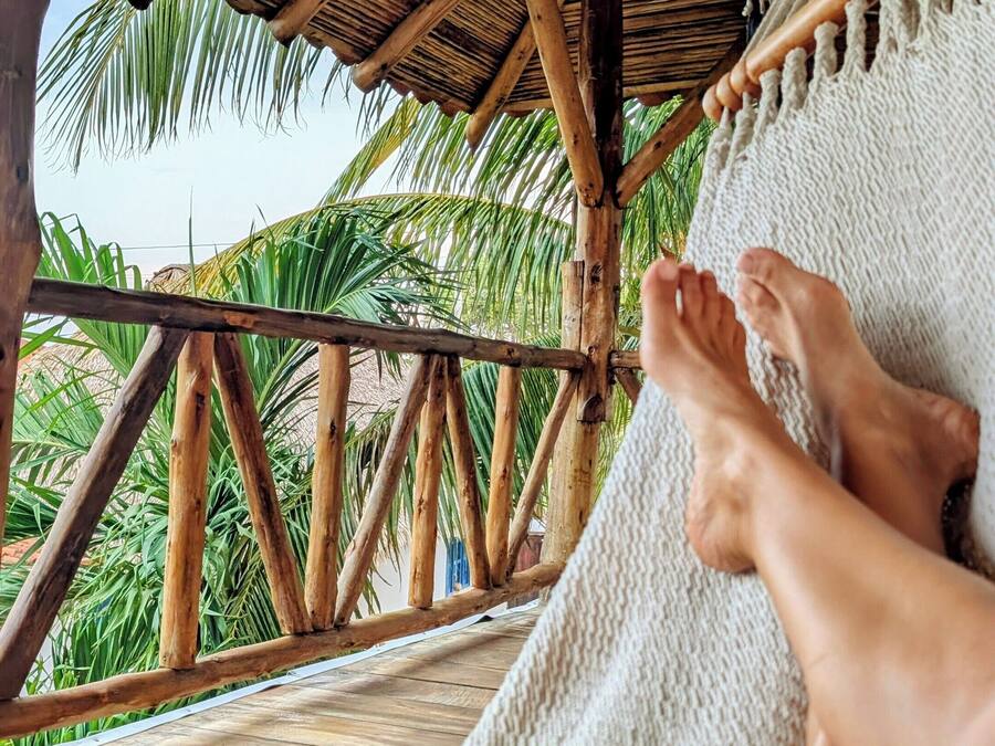 Una hamaca bajo una estructura de madera con vista a palmeras.