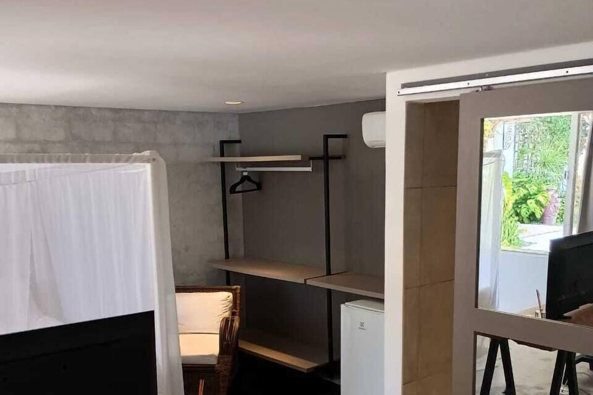 Une pièce moderne et minimaliste, équipée d’un bureau, d’une chaise, d’une étagère suspendue et d’un petit réfrigérateur.