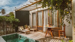 Área de piscina privativa ao ar livre com deck de madeira, uma mesa pequena e cadeiras.