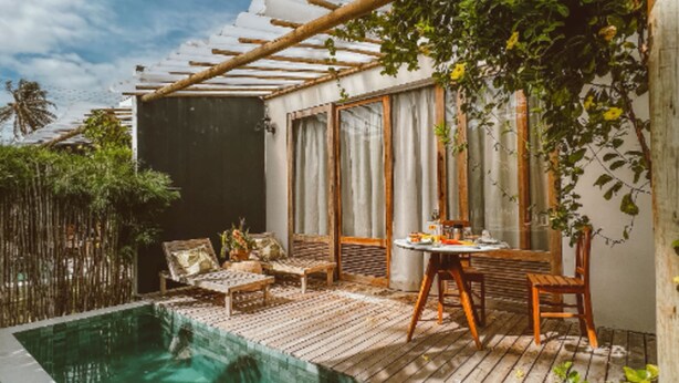 A private outdoor pool area with a wooden deck, a small table, and chairs. - Inn Tribus (Trairi)