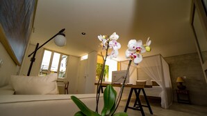 A room with a bed, a desk, a chair, a potted plant, and a lamp. - Inn Tribus (Trairi)