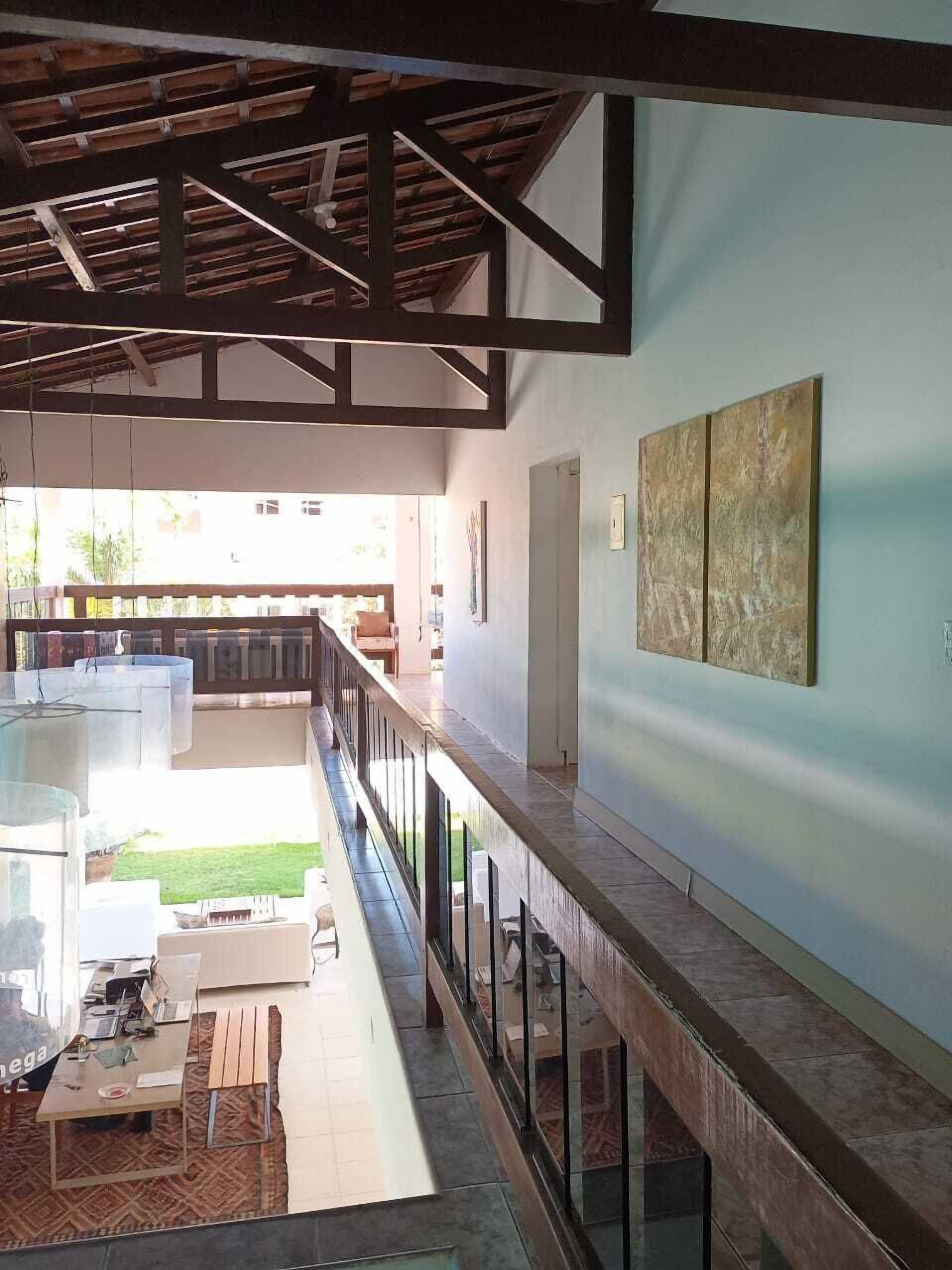 A spacious interior with a high ceiling, a balcony with a railing, and a view of the outdoors.